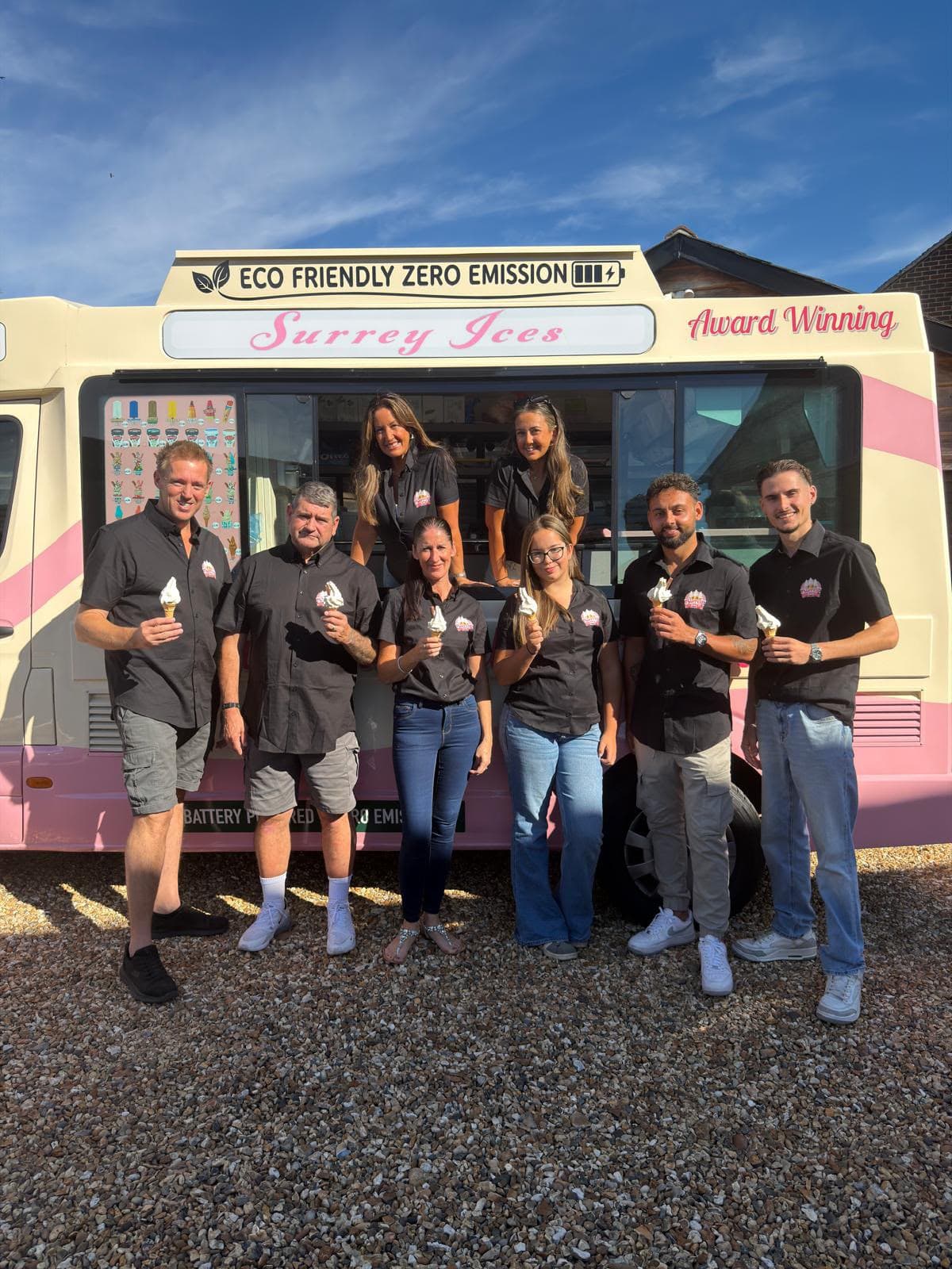 The Hampshire Ices team holding soft serve cones in front of a cream and pink van